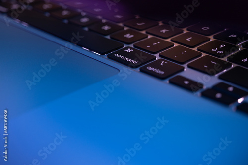Close-up of laptop keyboard and touchpad in neon lighting photo