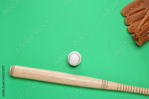 Baseball glove, bat and ball on green background, flat lay. Space for text