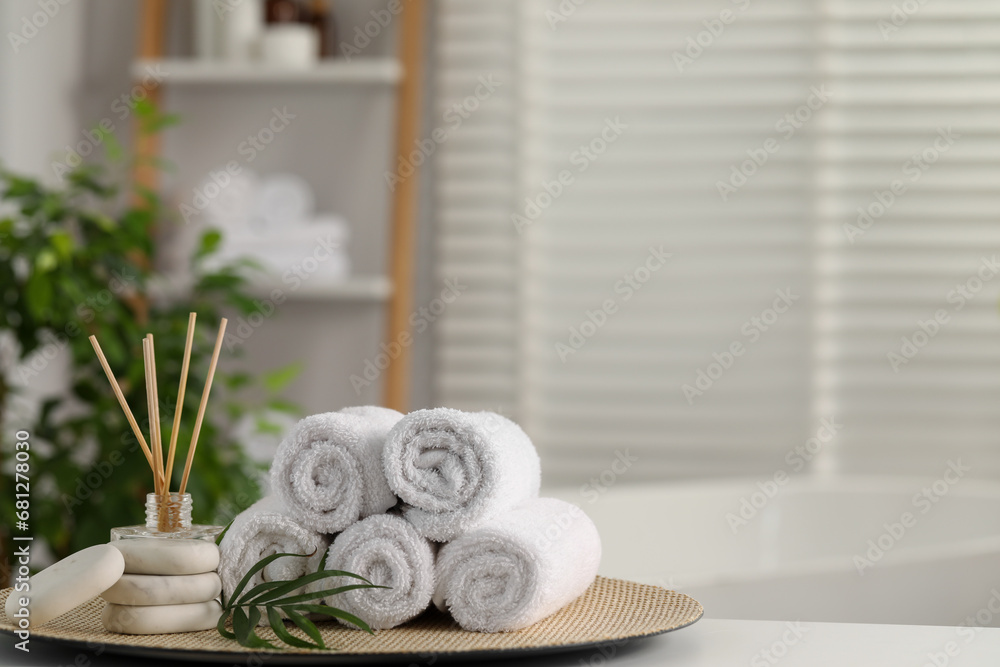 Spa composition. Towels, reed diffuser, stones and palm leaves on white table in bathroom, space for text