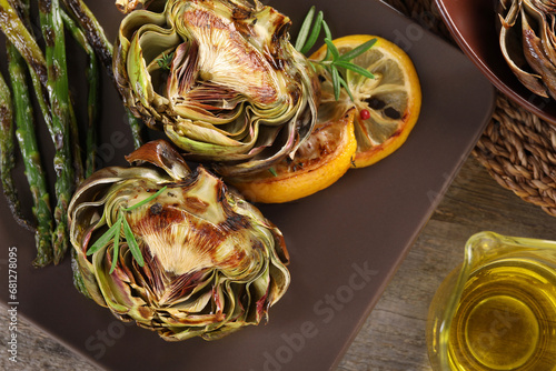 Tasty grilled artichoke served on wooden table, flat lay