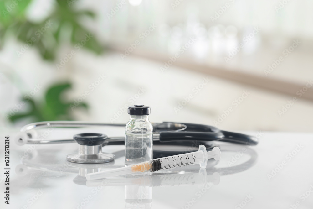 Glass vial, syringe and stethoscope on white table Glass vial, syringe and stethoscope on white table