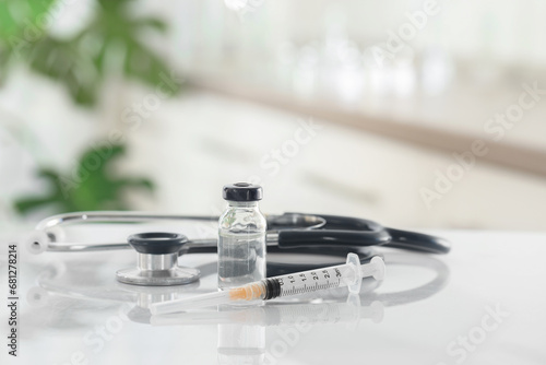 Glass vial, syringe and stethoscope on white table
