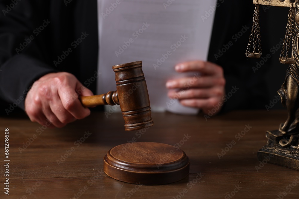 Judge with gavel sitting at wooden table, closeup Judge with gavel sitting at wooden table, closeup