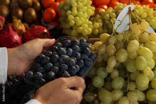 Woman picking fresh grapes at market, closeup