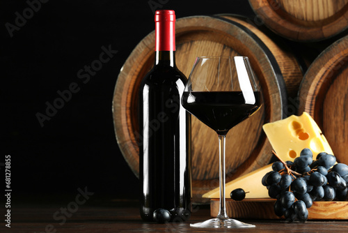 Delicious wine, wooden barrels, cheese and fresh grapes on table, space for text © New Africa