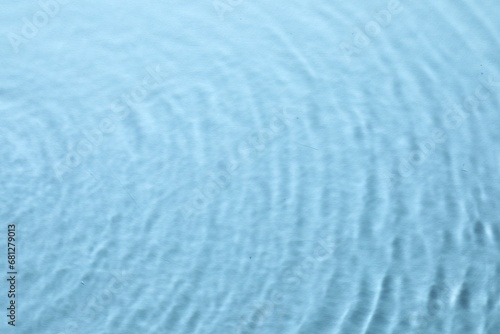 Rippled surface of clear water on light blue background, top view