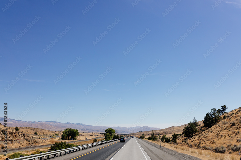 A picturesque asphalt road among the mountains. Highway in autumn on a sunny day with cars and trucks