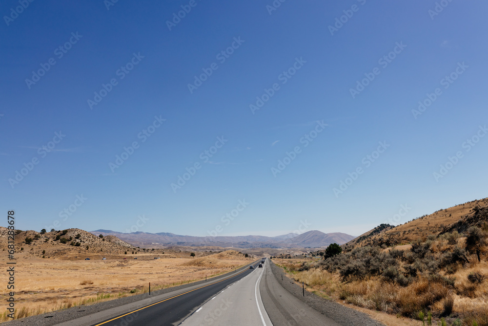 A picturesque asphalt road among the mountains. Highway in autumn on a sunny day with cars and trucks