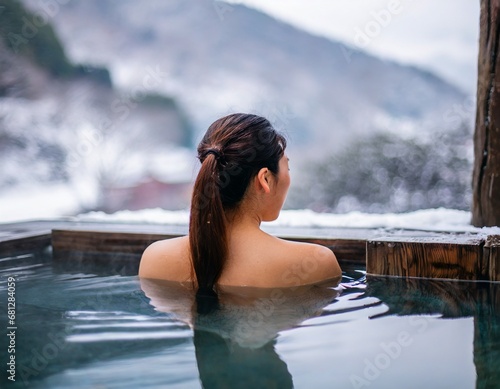  雪景色のきれいな温泉に浸かっている日本人女性の後ろ姿 