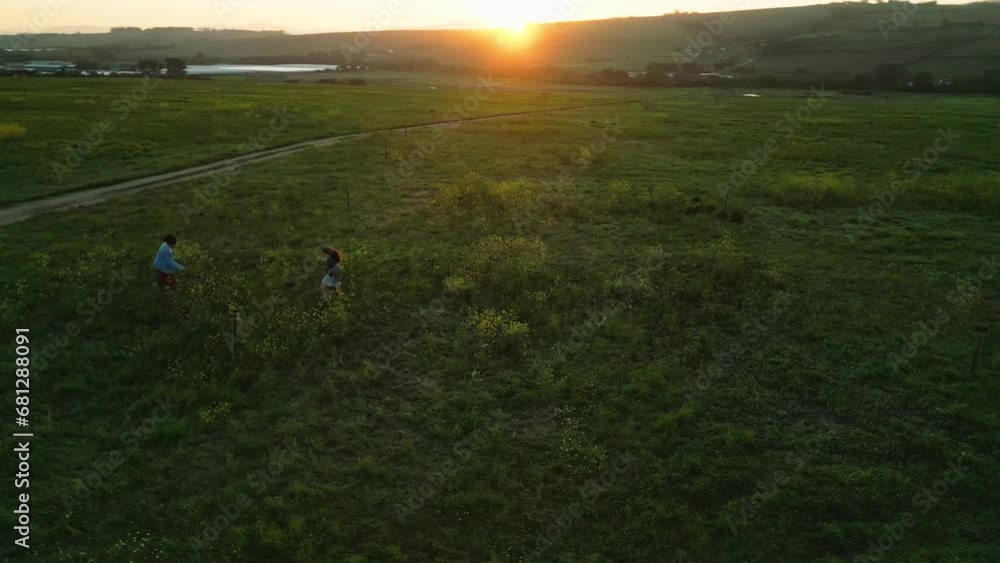 Aerial view, drone and people walking on grass in field and countryside in Europe with travel and freedom. Sustainability, farm and top with nature and outdoor with agriculture and sunset on holiday Aerial view, drone and people walking on grass in field and countryside in Europe with travel and freedom. Sustainability, farm and top with nature and outdoor with agriculture and sunset on holiday