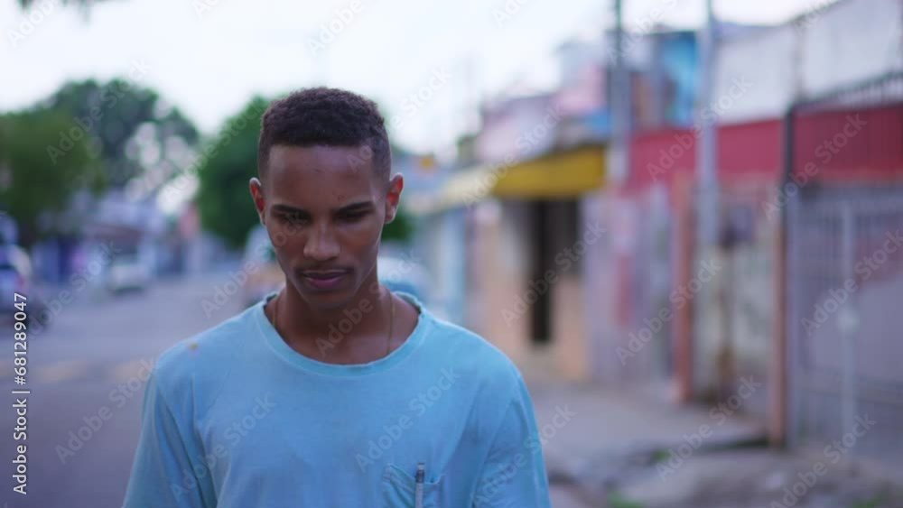 One introspective young black walking forward in street in thoughtful contemplation. Tracking shot in motion of a pensive South American Brazilian person thinking about life One introspective young black walking forward in street in thoughtful contemplation. Tracking shot in motion of a pensive South American Brazilian person thinking about life