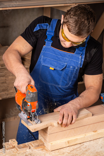 A carpenter using a jigsaw to cut wood cuts bars. Home repair concepts, close up.