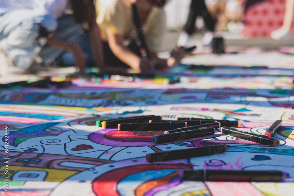 Fototapeta premium Process of drawing on asphalt and pavement, kids and children with crayons, chalk and markers, teens creating street art on the ground, graffiti and pictures on sideways, street painting festival
