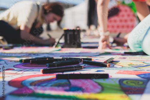 Process of drawing on asphalt and pavement, kids and children with crayons, chalk and markers, teens creating street art on the ground, graffiti and pictures on sideways, street painting festival photo