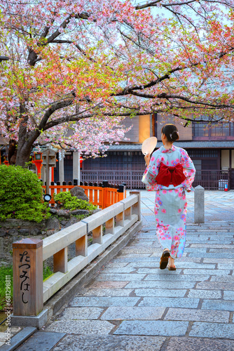 Young Japanese woman in traditional Kimono dress strolls on Tatsumi bashi bridge  over Shirakawa river in Gion district, Kyoto, Japan photo