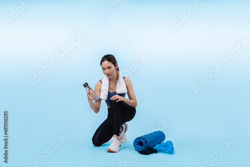 Athletic and sporty asian woman resting and drink water after intensive cardio workout training. Healthy exercising and fit body care lifestyle pursuit in studio shot isolated background. Vigorous photo