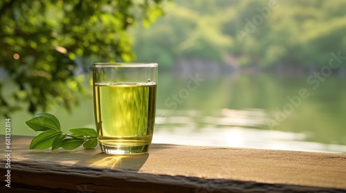 a glass filled with vibrant green tea, elegantly placed on a table against a backdrop of serene nature