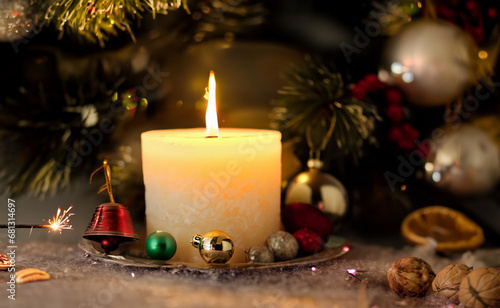 Christmas decoration with burning candle and ornaments on wooden background.