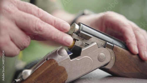 Double-barrelled shotgun cocked open being loaded with shells. Handheld photo