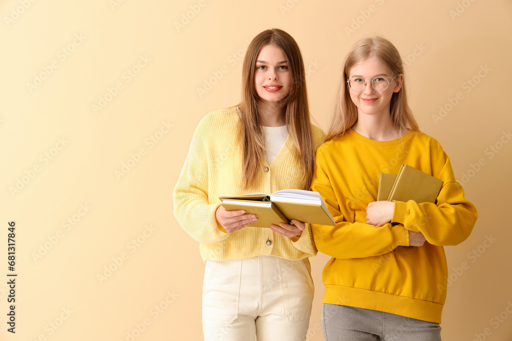 Fototapeta premium Happy female students books on pale yellow background