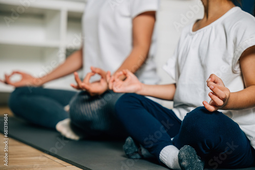 A mother and daughter enjoy leisure time by meditating and doing yoga in their living room. Their togetherness and concentration create a peaceful family moment filled with vitality and joy.