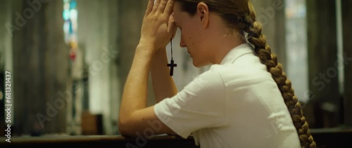 Girl church parishioner prays on her knees in cathedral. A sincerely believing woman close-up. photo