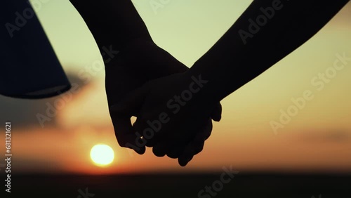 Separation of hands of man of woman. Closeup of guy lets go of girls hand, separation. Family at sunset. Pair of man, woman separate their hands in front of sun. Separation, separation, quarrel. photo