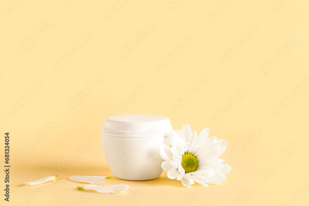Jar of cosmetic product with chamomile flower on color background