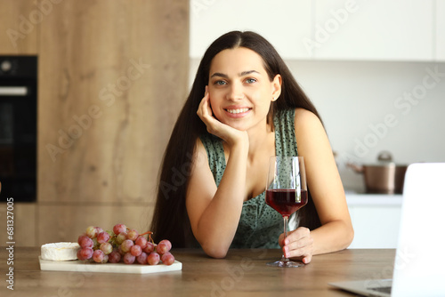 Young woman with glass of wine in kitchen