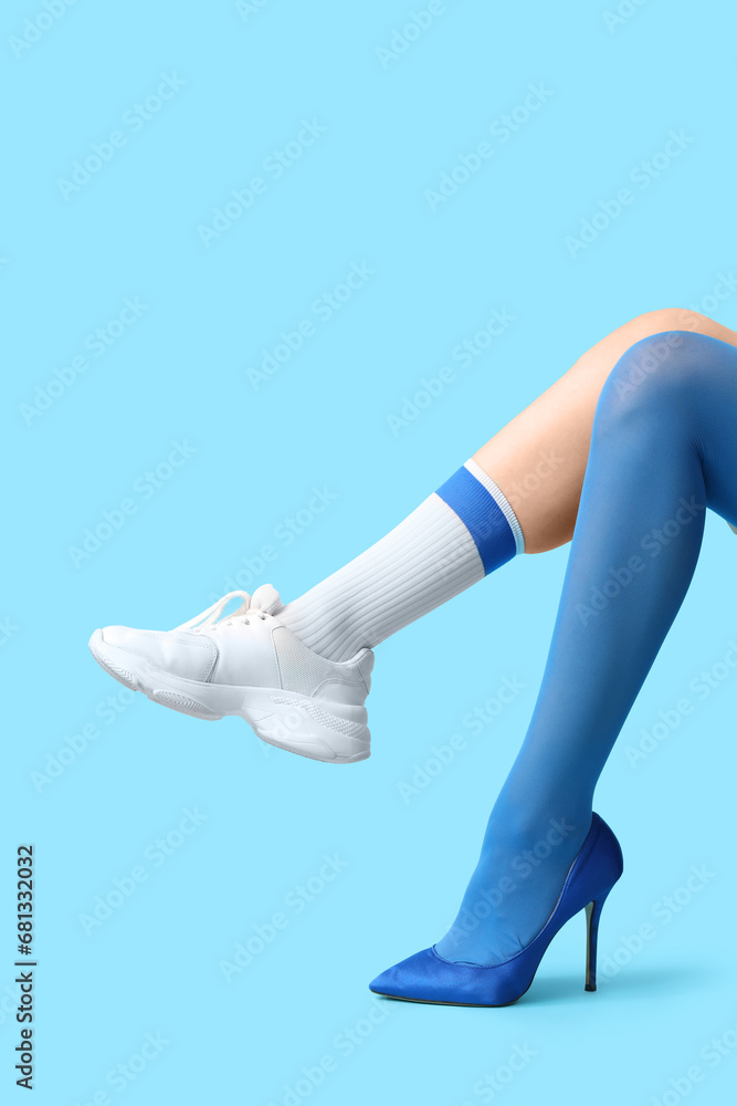 Legs of young woman in different stylish shoes on blue background Legs of young woman in different stylish shoes on blue background