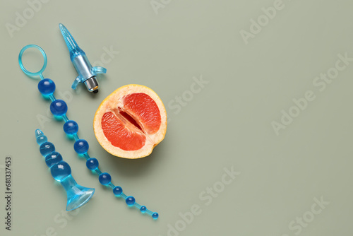 Anal plugs from sex shop and half of tasty grapefruit on green background