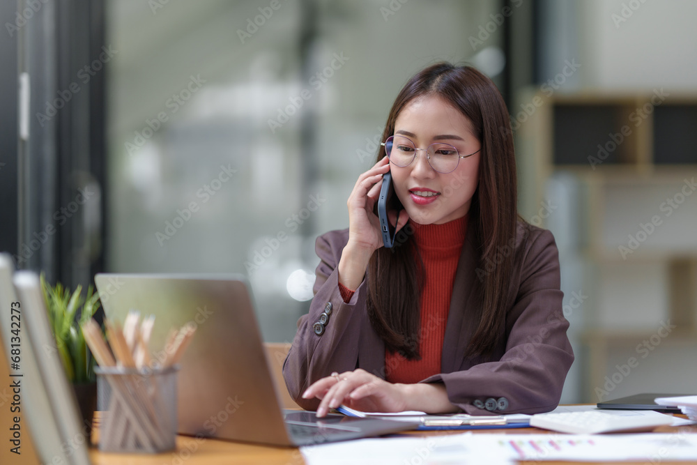 Asian businesswoman talking on the phone professionally in her office. Asian businesswoman talking on the phone professionally in her office.