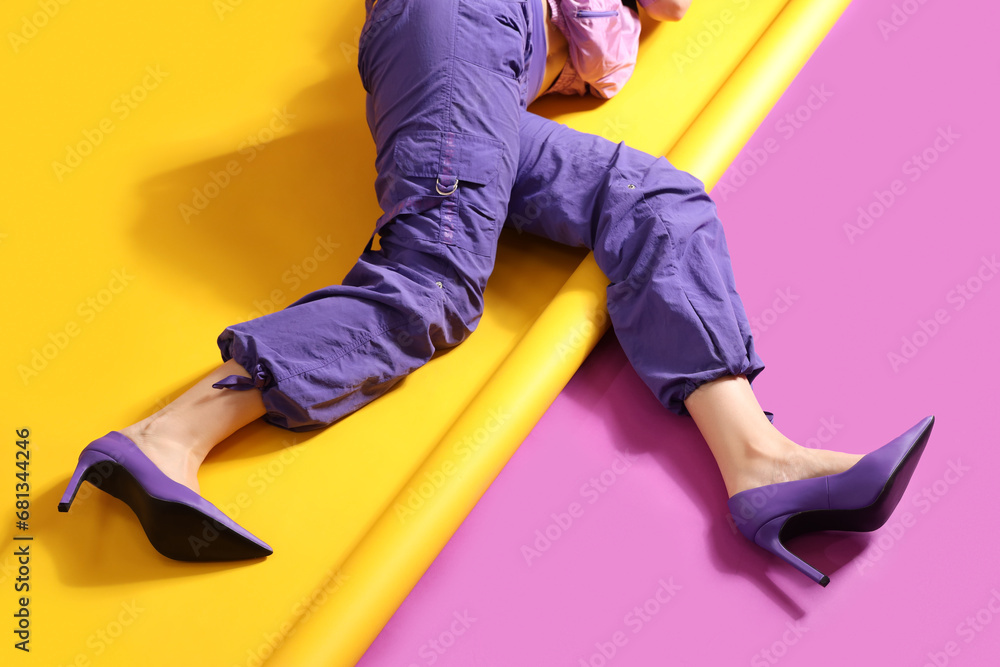 Naklejka premium Woman in stylish high heeled shoes lying on color background