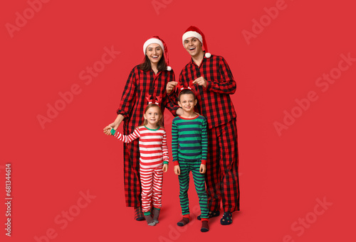 Happy family in Christmas pajamas on red background