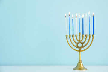 Menorah with burning candles on table in living room, closeup. Hanukkah celebration