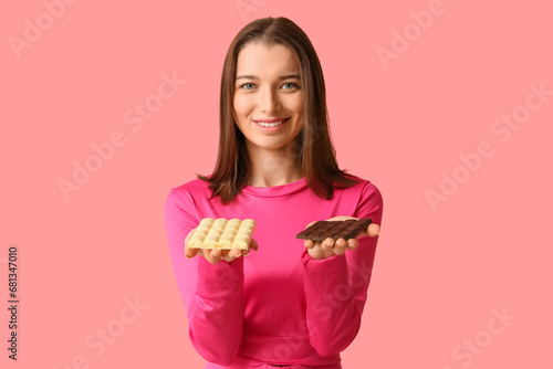 Young woman with different chocolate bars on pink background