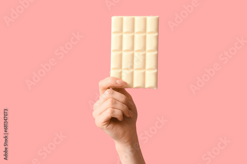Female hand with white chocolate bar on pink background