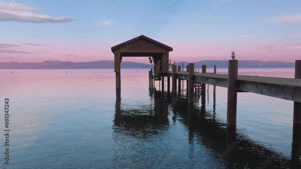 Cinematic view of calm Tahoe lake with rippling waters and reflecting pastel pink blue sky. Covered boat parking at lake shore during colorful cloudy sunset at mountain lake. Scenic copy background 4K Cinematic view of calm Tahoe lake with rippling waters and reflecting pastel pink blue sky. Covered boat parking at lake shore during colorful cloudy sunset at mountain lake. Scenic copy background 4K