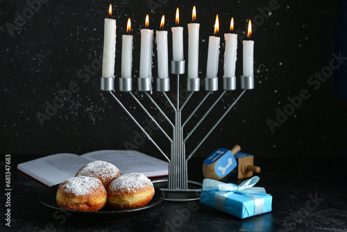 Menorah, Torah, donuts and gift for Hanukkah celebration on dark background photo