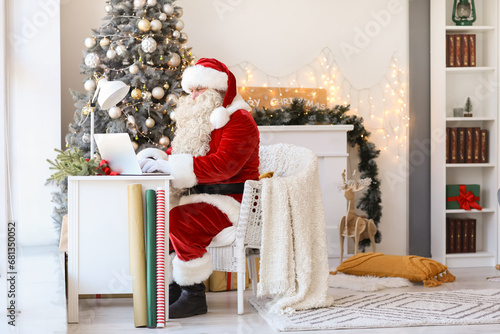 Santa Claus using laptop at...