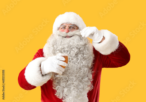 Santa Claus with glass of beer on yellow background © Pixel-Shot