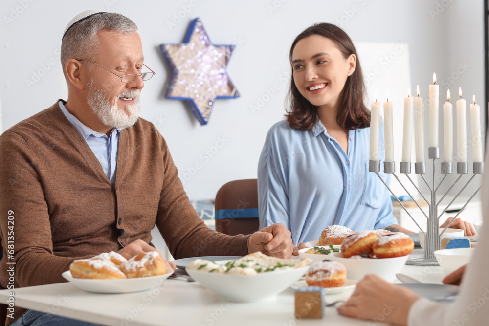 Young woman having dinner with her father at home on Hanukkah Young woman having dinner with her father at home on Hanukkah