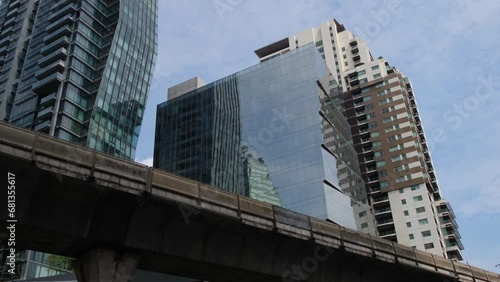 A building on Sukhumvit street with the BTS elevated railway, blue sky and clouds, Bangkok, Thailand photo