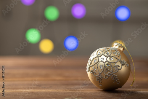 Christmas composition. Golden ball on wooden table on sparkling background