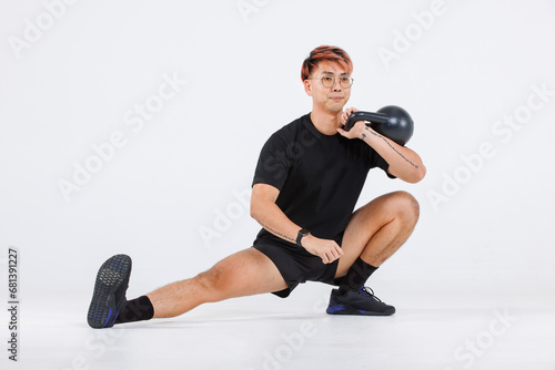 Isolated cutout full body studio shot of strong Asian male fitness athlete sportsman trainer model in casual sport workout outfit lifting kettlebell training exercising stretching on white background