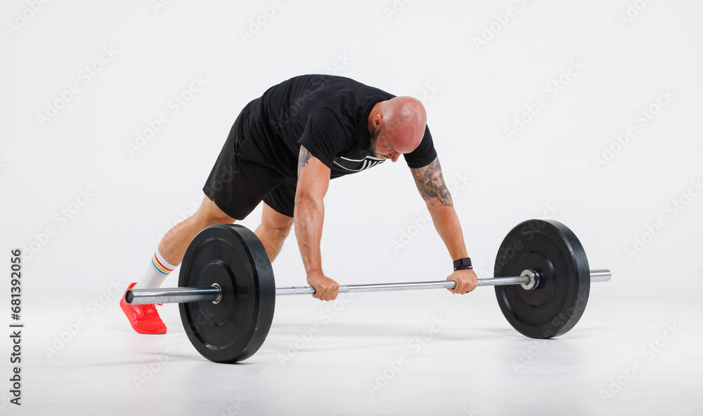 Fototapeta premium Isolated cutout full body studio shot strong Caucasian bald tattoo male fitness athlete sportsman trainer model in casual sport workout outfit push up on barbell training exercise on white background
