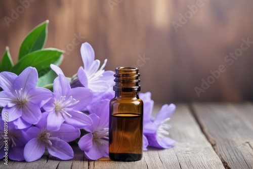 Essential oil in a small glass bottle with purple flowers on a wooden background