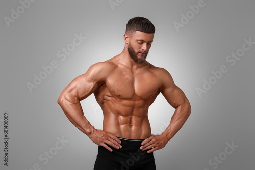 Young bodybuilder with muscular body on light grey background