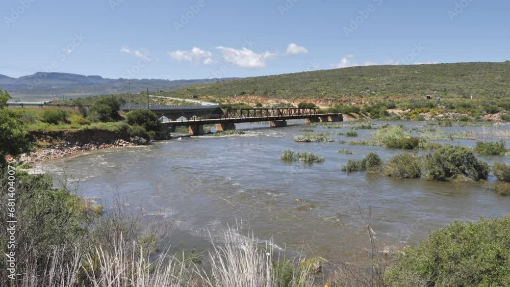 Deep and strong flowing Olifants River has eroded away riverbank leading to Clanwilliam road bridge and flooded vegetation Deep and strong flowing Olifants River has eroded away riverbank leading to Clanwilliam road bridge and flooded vegetation