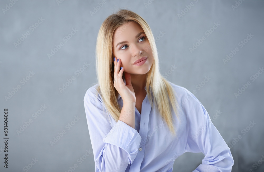 Portrait of a sexy woman in a man's shirt wearing on a gray background looks at the camera and smiling look advice to give wants objections are not accepted. - obrazy, fototapety, plakaty 